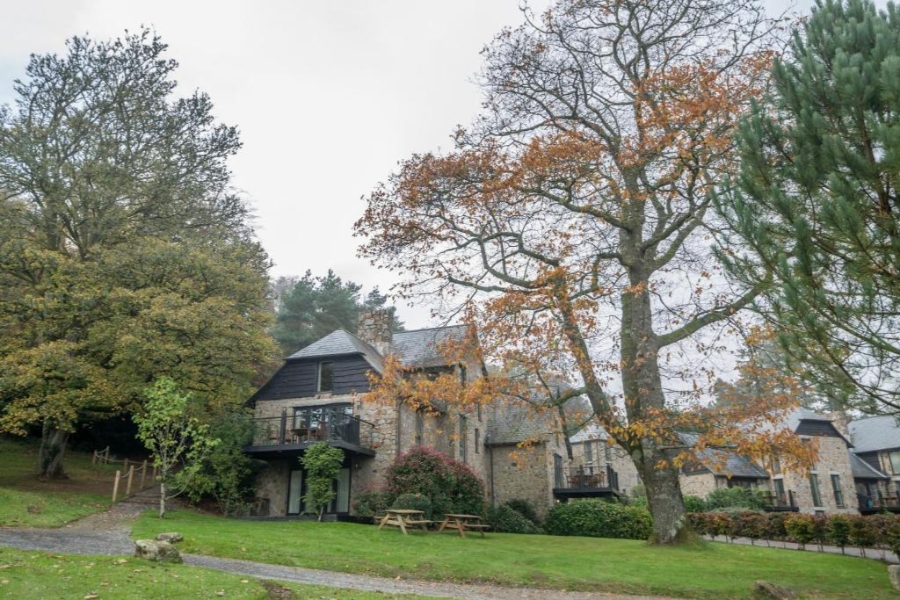 Bovey Castle, a grand structure, is nestled among lush trees and green grass in the United Kingdom.