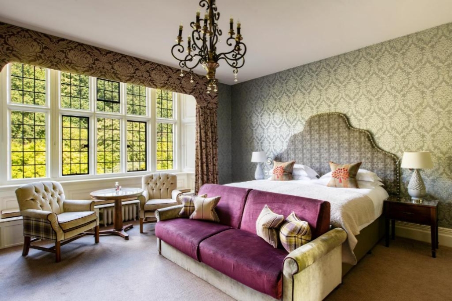 Interior of a large bedroom at Bovey Castle, highlighted by a purple couch and a stunning chandelier overhead.