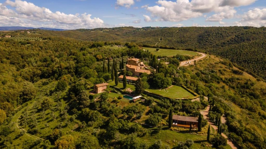 Scenic aerial perspective of the Italian countryside showcasing Castello di Vicarello amidst rolling hills and fields.