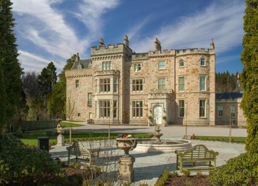 Crossbasket Castle in the UK, surrounded by lush trees and bushes, showcasing its historic architecture.