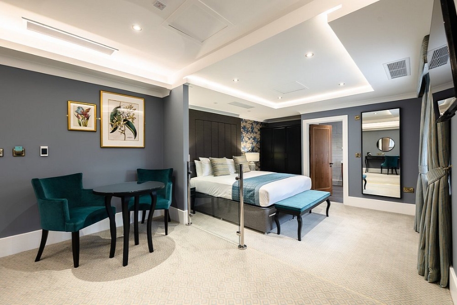 Hotel bedroom featuring a bed, desk, and chair, showcasing elegant decor and a cozy atmosphere.