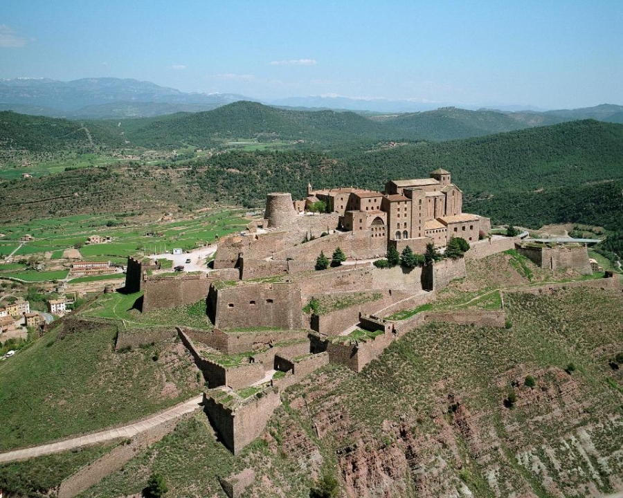Panoramic view of Parador de Cardona castle, nestled among lush mountains and rolling hills.