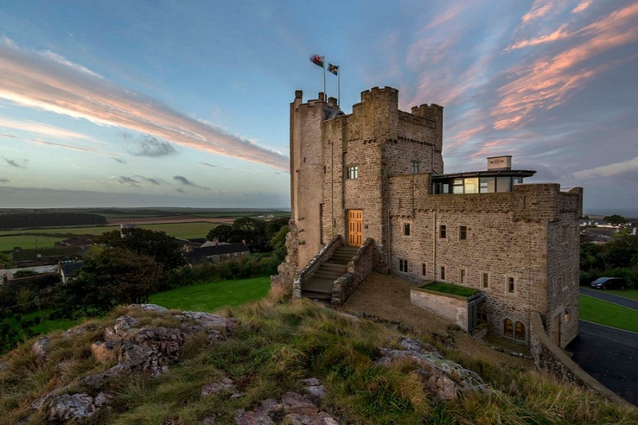 Roch Castle perched on a hill, overlooking the ocean, showcasing its historic stone architecture against a clear sky.