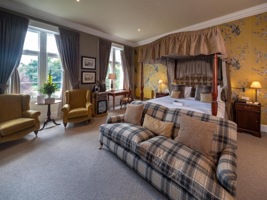 Luxurious bedroom featuring a four-poster bed and an elegant chair, showcasing the comfort of Schloss Roxburghe Golf Resort.