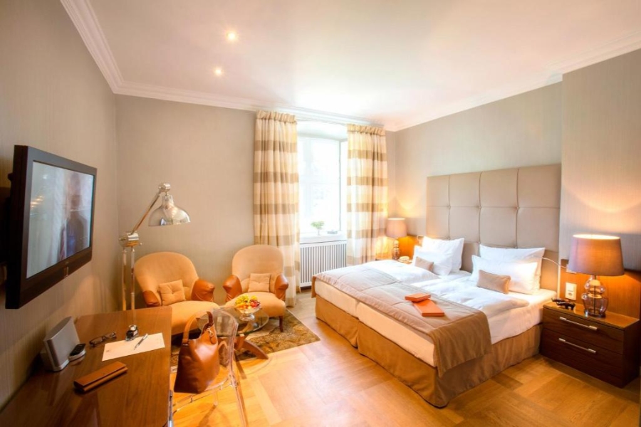 Interior view of a hotel room showcasing a bed, a TV, and a chair, designed for comfort and relaxation.